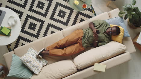 Afro-American-Man-Lying-on-Couch-and-Using-Smartphone